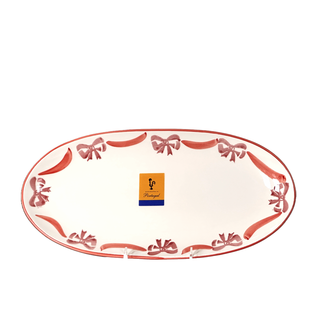 Decorative oval plate with red bows and a brand logo on a white background
