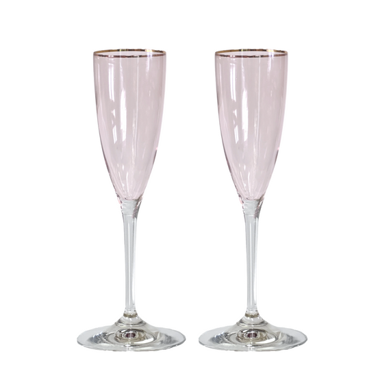 Two pink champagne flutes with gold rims on a white background